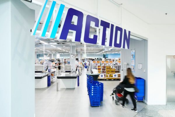 Punto vendita Action. Ingresso negozio Action con cliente e carrello. Vendite Action in crescita.