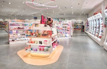 Interni DM: scaffali cosmetici, illuminazione neon rosa. Prodotti bellezza, cura personale. Design moderno, luminoso.