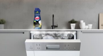 Flacone di gel lavastoviglie Dual Power con carboni attivi posizionato su una cucina moderna con lavastoviglie aperta.