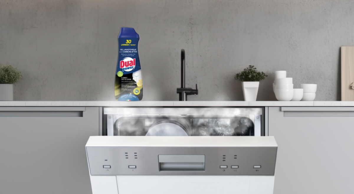 Flacone di gel lavastoviglie Dual Power con carboni attivi posizionato su una cucina moderna con lavastoviglie aperta.