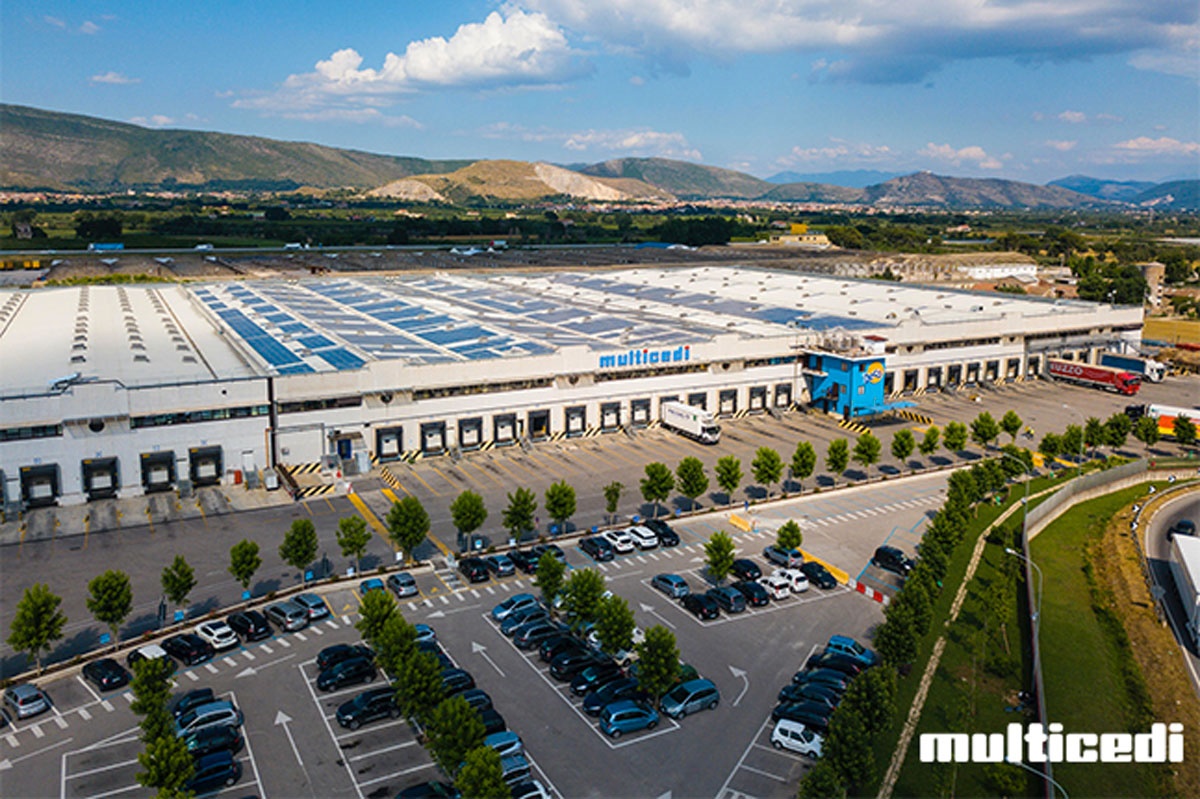 Veduta aerea del polo logistico Multicedi con magazzini, parcheggio e camion, simbolo del fatturato record 2025.
