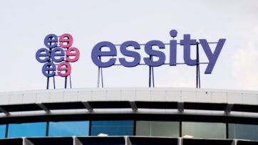 Insegna aziendale con logo e scritta blu Essity posizionata sul tetto di un moderno edificio per uffici.