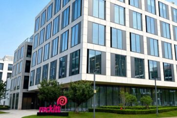 Facciata del nuovo hub globale Reckitt a Shanghai con logo aziendale su moderno edificio in vetro e acciaio.