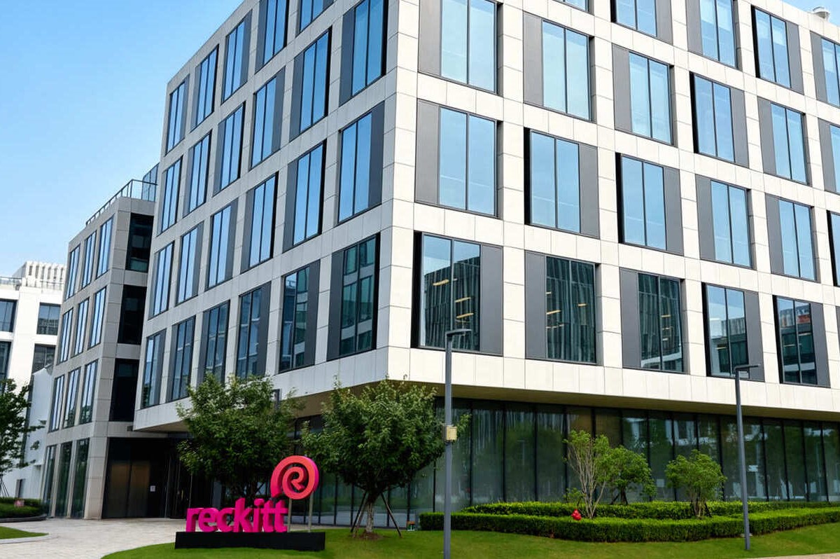 Facciata del nuovo hub globale Reckitt a Shanghai con logo aziendale su moderno edificio in vetro e acciaio.