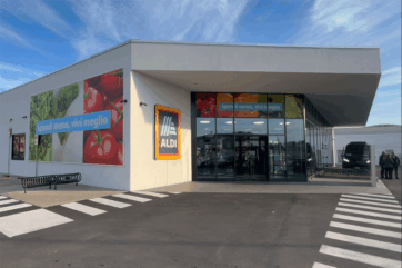 Punto vendita Aldi Italia con insegna, vetrate e slogan Spendi meno, vivi meglio per la strategia di convenienza.