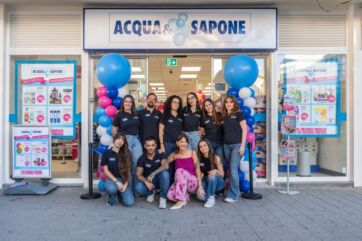 Gruppo di dipendenti davanti al negozio Acqua & Sapone in Spagna con palloncini blu e bianchi all'ingresso.