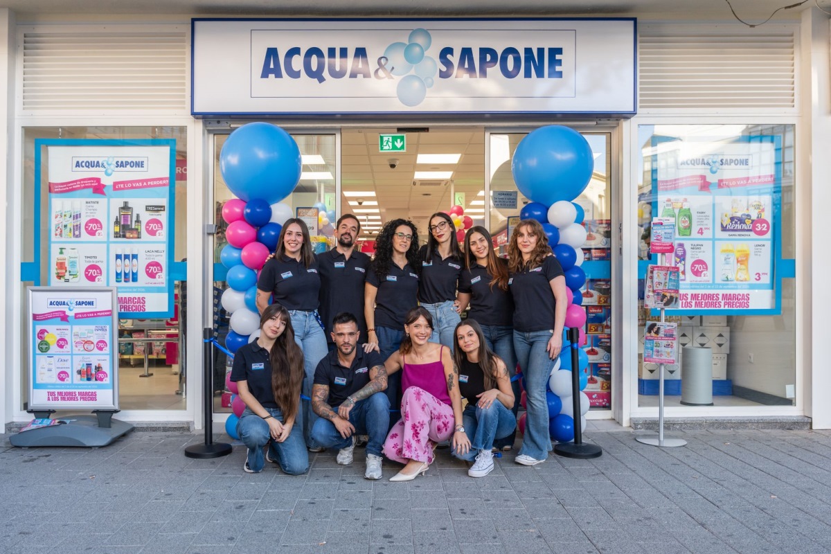 Gruppo di dipendenti davanti al negozio Acqua & Sapone in Spagna con palloncini blu e bianchi all'ingresso.
