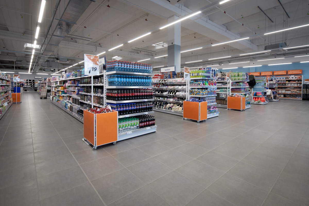 Supermercato con corsie ampie, scaffali pieni di prodotti e display arancioni per il repertorio 2025.