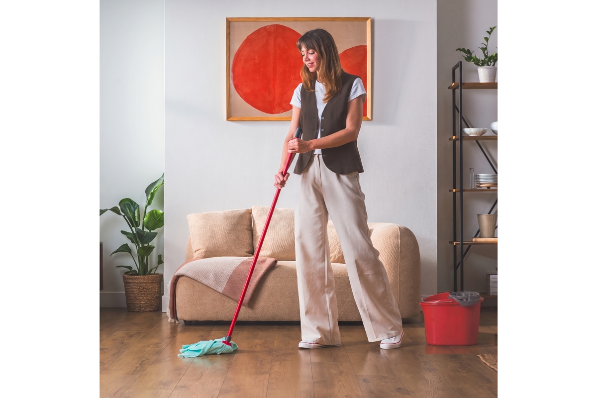 Donna lava pavimento in legno con SuperMocio Pro Clean in microfibra Vileda, secchio rosso accanto.