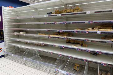 Scaffali del supermercato quasi vuoti durante uno sciopero dei trasporti, con poche confezioni di pane rimaste.