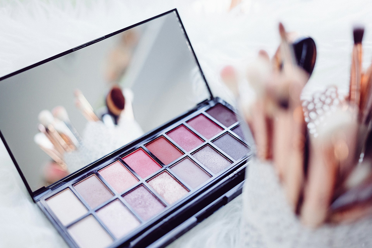 Palette ombretti dai toni rosati e pennelli. Beauty e make-up per il consumo di fragranze e cosmetici in Europa.