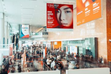 Folla a Cosmoprof Asia, fiera beauty. Stand promozionali, atmosfera vivace. Hub strategico per il settore beauty in Asia.