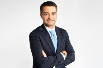 Francesco Casella, nuovo presidente di Naïma, in abito blu e cravatta azzurra su sfondo bianco.