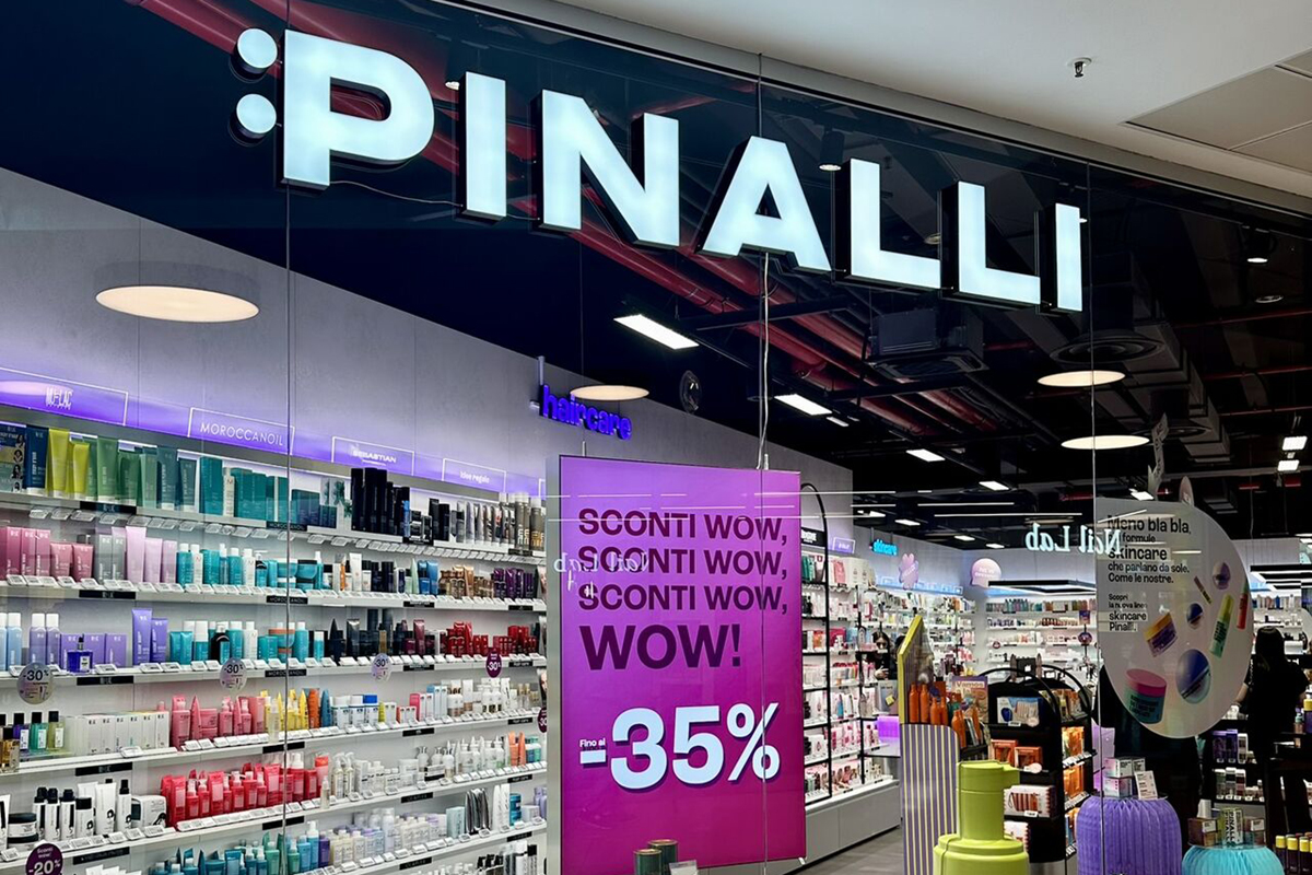 Insegna luminosa del negozio Pinalli in Lombardia con scaffali di prodotti di bellezza e cartello promozionale al -35%.