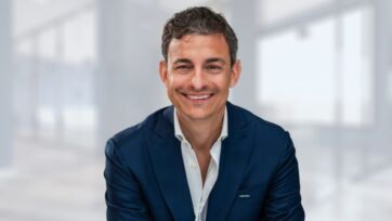 Riccardo Mascambruno, nuovo leader di Shiseido Italia, ritratto in giacca blu su sfondo da ufficio sfocato.