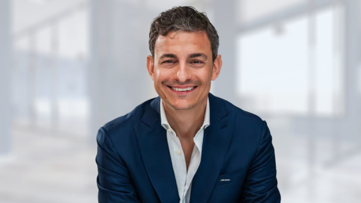 Riccardo Mascambruno, nuovo leader di Shiseido Italia, ritratto in giacca blu su sfondo da ufficio sfocato.
