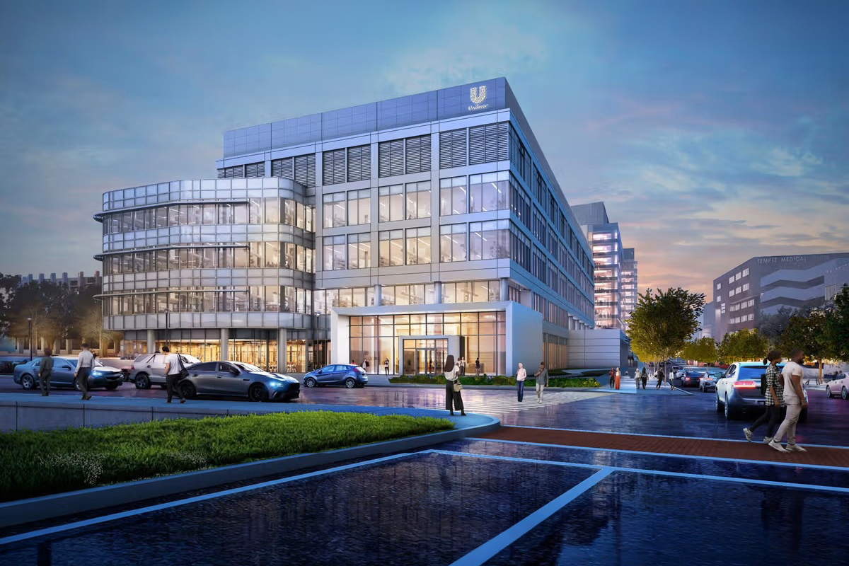 Nuovo hub Unilever a New Haven, USA: edificio moderno in vetro con uffici, parcheggio e persone all'ingresso al tramonto.