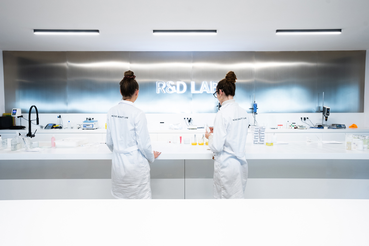 Ricercatrici in camice bianco lavorano nel laboratorio R&D di Niche Beauty Lab per lo sviluppo di prodotti cosmetici.
