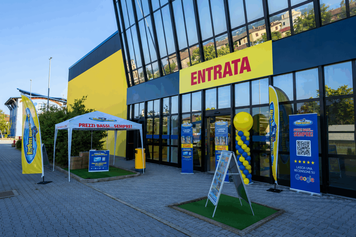 Facciata di un punto vendita Risparmio Casa con insegna Entrata, gazebo promozionale e cartellonistica pubblicitaria.