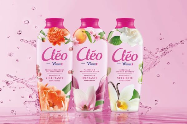 Tre flaconi di bagnodoccia Cléo Paglieri con nuove formule e packaging floreale su sfondo rosa con spruzzi d'acqua.