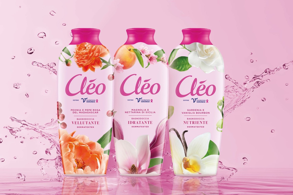 Tre flaconi di bagnodoccia Cléo Paglieri con nuove formule e packaging floreale su sfondo rosa con spruzzi d'acqua.
