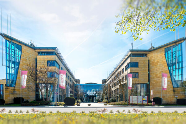 Moderno edificio della sede centrale di Cosnova Beauty con facciata in pietra, vetrate e bandiere aziendali rosa.