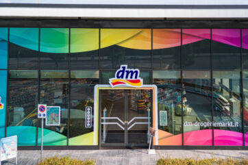 Facciata di un negozio dm drogerie markt in Italia con vetrate colorate e logo dell'insegna all'ingresso.