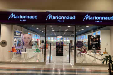Vetrina del negozio di profumeria Marionnaud Paris con insegna luminosa, espositori di cosmetici e promozioni in corso.