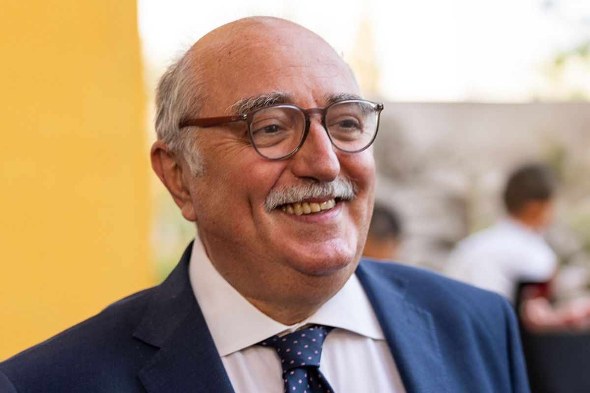 Ritratto in primo piano di Paolo Dalco, uomo sorridente con occhiali, giacca blu, camicia bianca e cravatta a pois.