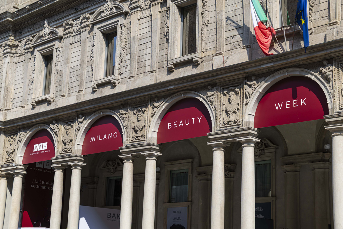 Facciata di Palazzo Giureconsulti a Milano con arcate e bandiere, allestita per la Milano Beauty Week 2025