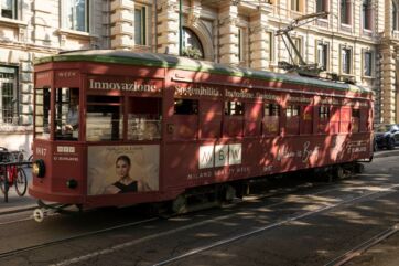 Tram storico rosso brandizzato Milano Beauty Week con scritte su innovazione e sostenibilità tra le vie di Milano.