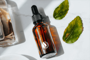 Siero viso NATRUE in flacone ambra con contagocce e foglie verdi, cosmetico naturale contro il greenwashing