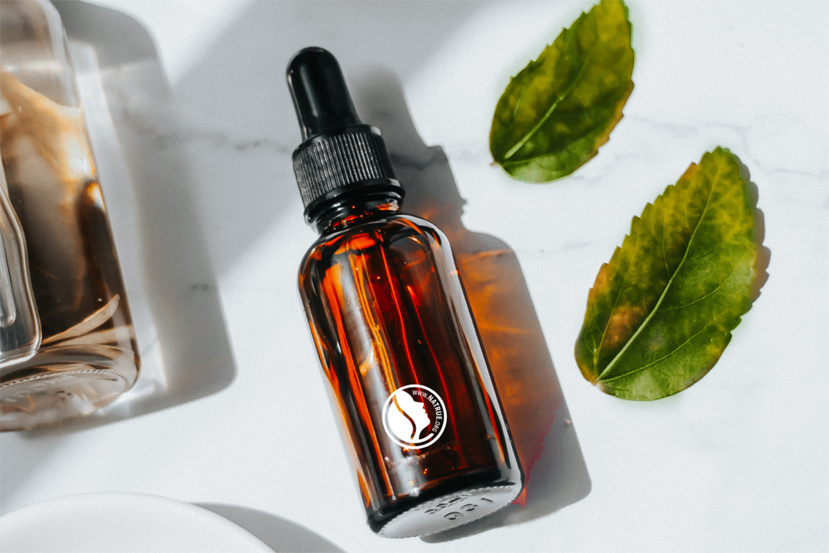 Siero viso NATRUE in flacone ambra con contagocce e foglie verdi, cosmetico naturale contro il greenwashing