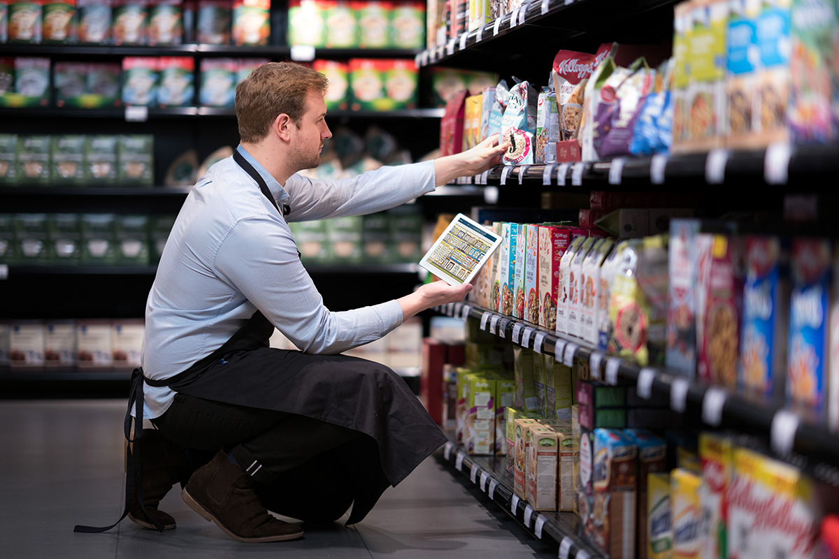 Addetto retail con tablet analizza scaffali di prodotti alimentari: AI nel retail.