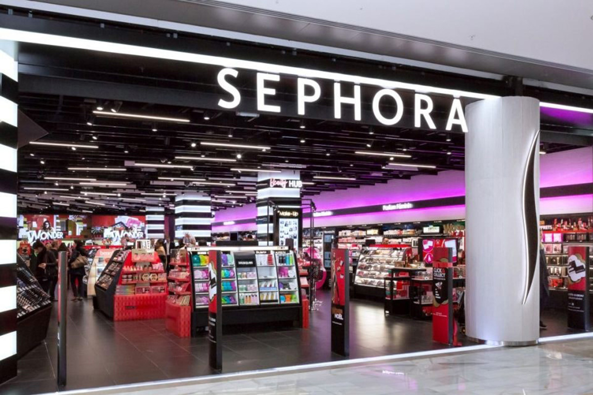 Negozio Sephora con insegna luminosa, espositori di cosmetici e clienti: shop-in-shop Marks & Spencer nel Regno Unito.